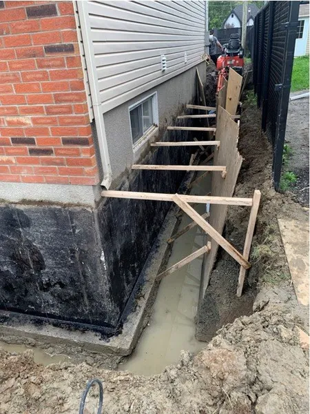 Préparation du mur de solage pour l’installation d’une membrane d’étanchéité au Québec.
